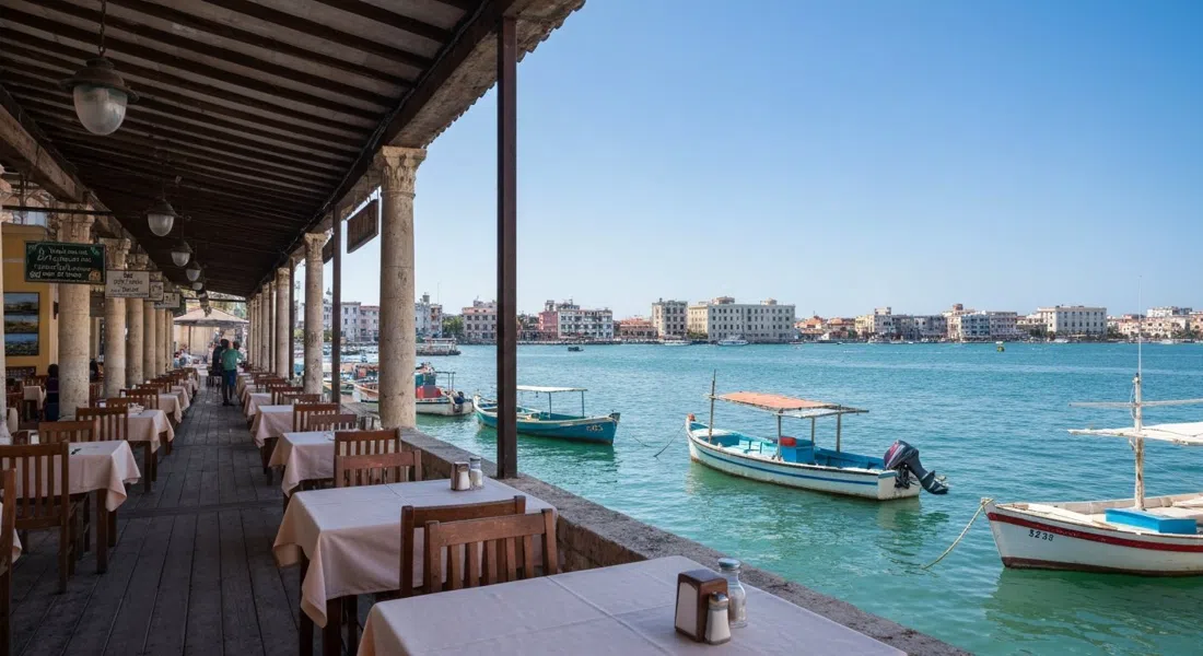 la terrazza sul porto a La Terraza de Cojímar su Calle Real, tavoli affacciati sull'acqua con barche da pesca e foto di Raúl Corrales all'interno